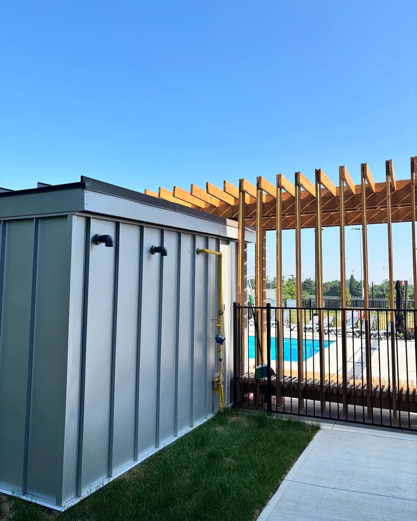 A modern pool shed paired with an open timber pergola.