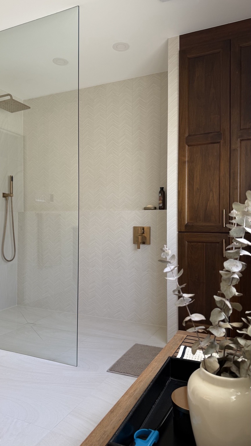 White patterned tile, brass fixtures and rich wood cabinetry.
