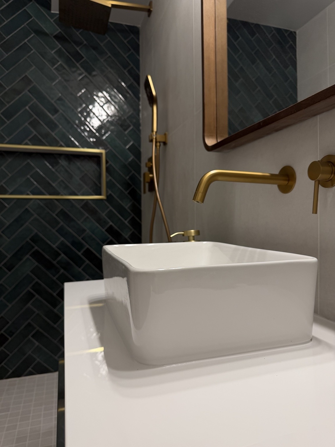 Green herringbone shower tile and gold fixtures