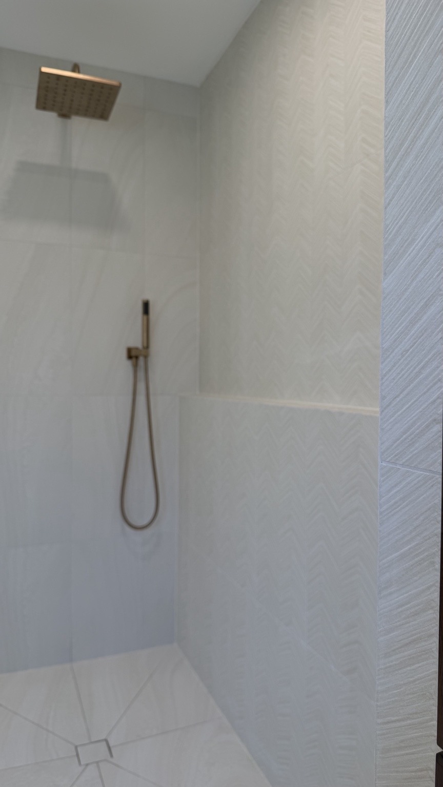 A closer view of patterned shower tile and brass fittings.