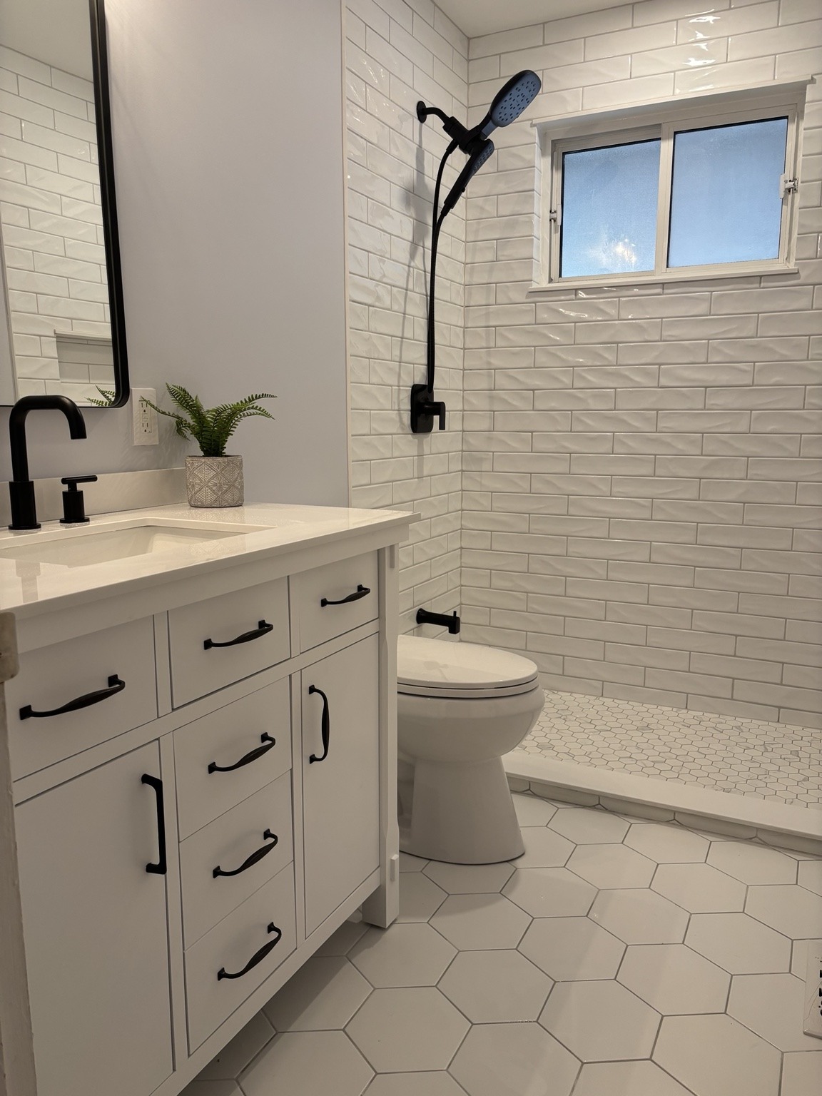 Subway shower tile, hexagon flooring and black hardware.